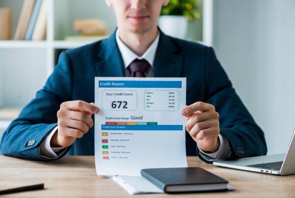 Does Credit Score Affect Legal Funding? blog. Photo of a man at a desk holding up a credit score report.